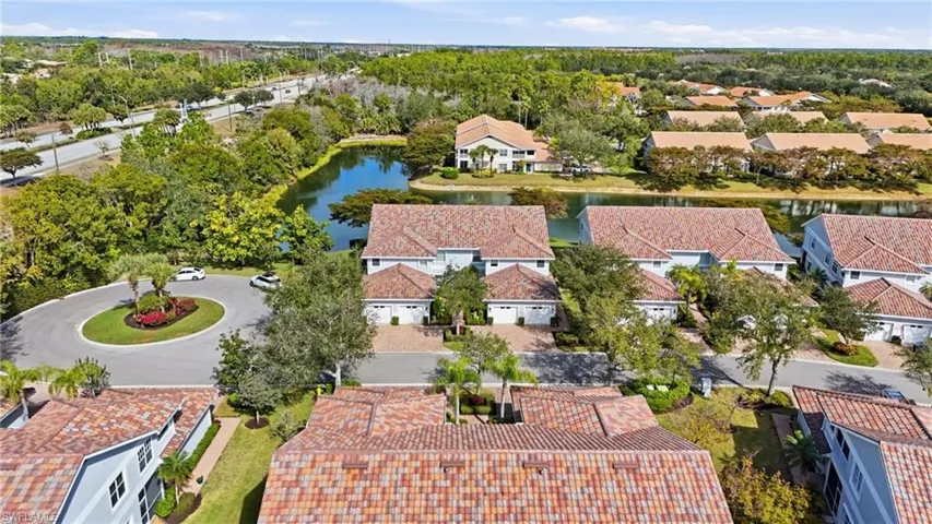 Aerial view of residential area with a large body of water and a tree filled landscape