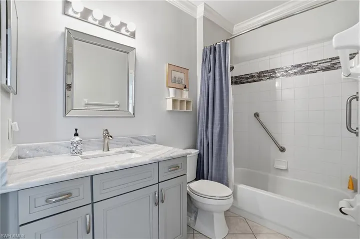 Full bath with vanity, shower / bath combination with curtain, crown molding, and light tile patterned floors