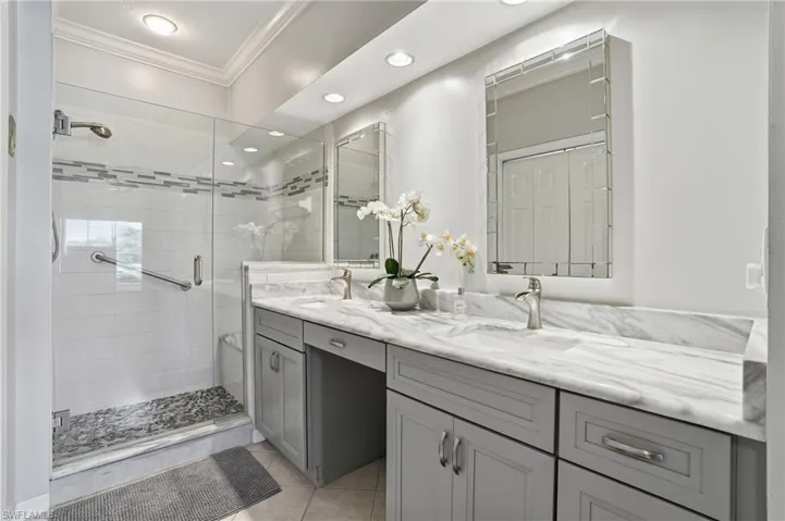 Bathroom with double vanity, crown molding, a shower stall, recessed lighting, and light tile patterned flooring