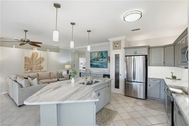 Kitchen with gray cabinetry, stainless steel appliances, pendant lighting, a ceiling fan, and light stone counters