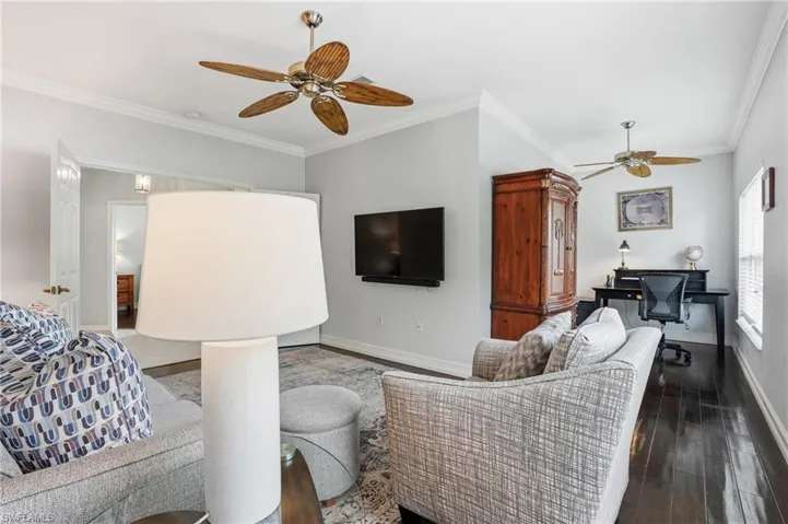 Living area featuring ornamental molding, ceiling fan, an office area, and wood-type flooring