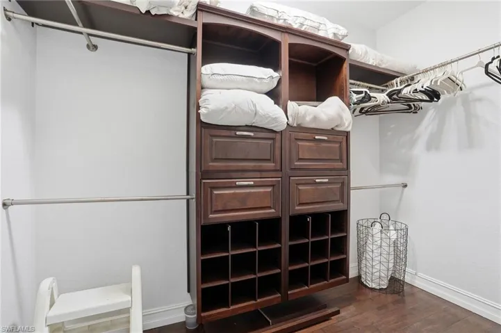 Walk in closet with dark wood finished floors