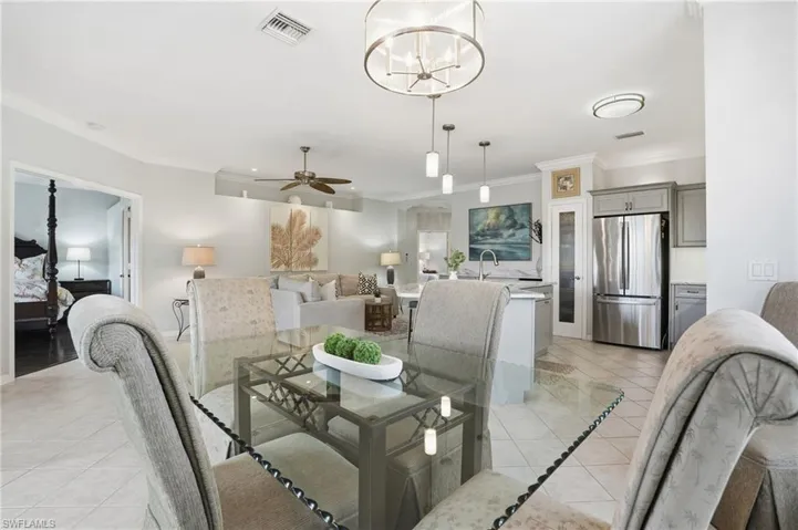 Dining area featuring a ceiling fan, light tile patterned flooring, ornamental molding, and a chandelier