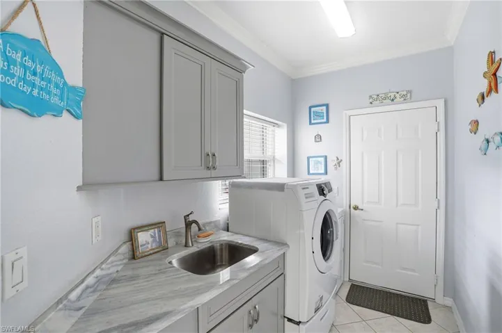 Laundry area featuring cabinet space, crown molding, light tile patterned floors, and independent washer and dryer