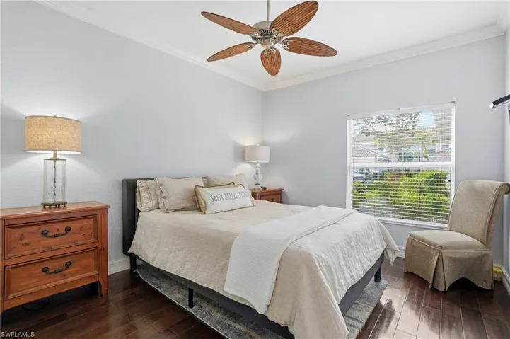 Bedroom featuring dark wood-style flooring, ornamental molding, and a ceiling fan