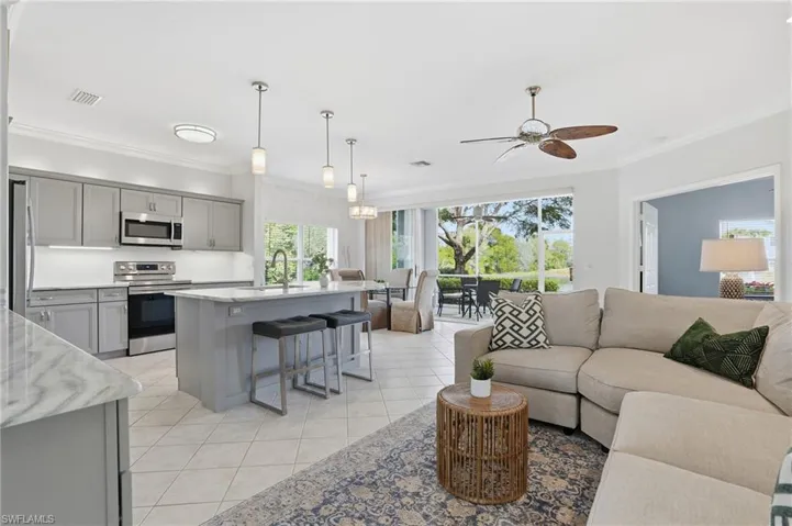 Living room featuring crown molding, light tile patterned floors, and a ceiling fan
