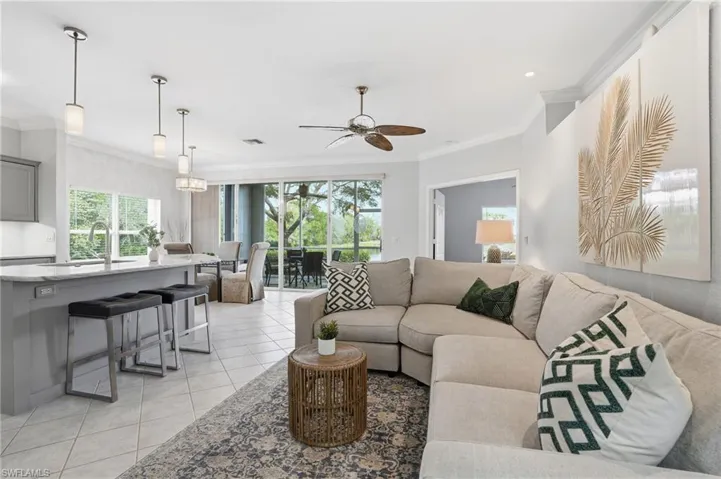 Living room featuring ornamental molding, light tile patterned floors, and a ceiling fan