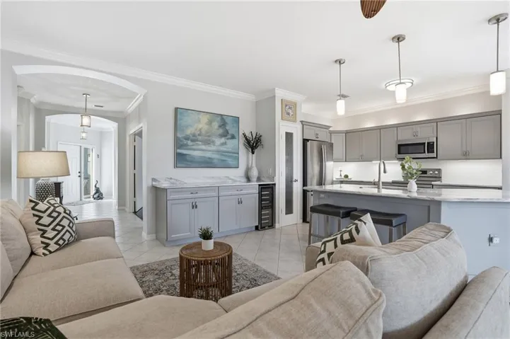 Living room with arched walkways, ornamental molding, wine cooler, and light tile patterned flooring