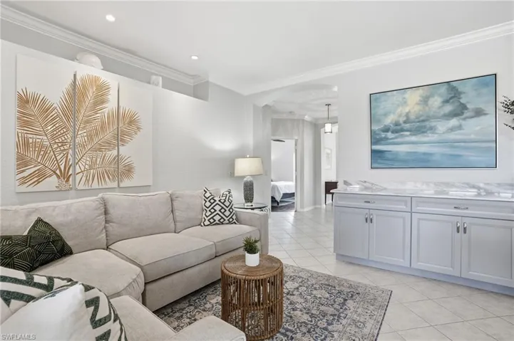 Living room with crown molding, light tile patterned floors, and arched walkways