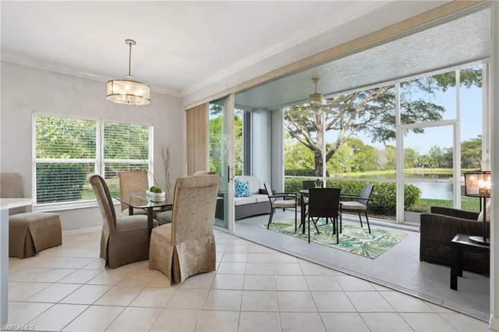 Dining space with a water view, ceiling fan, light tile patterned floors, and crown molding