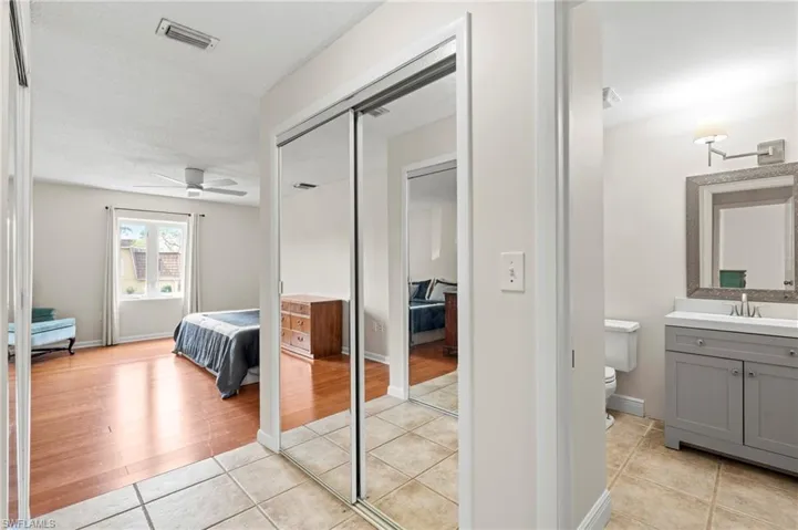 Bedroom featuring light tile patterned floors, a sink, ensuite bath, and a closet