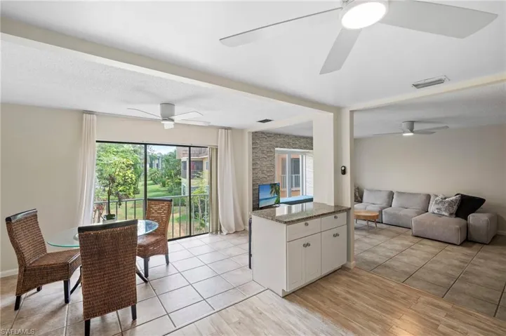 Kitchen featuring ceiling fan, open floor plan, stone counters, white cabinets, and light wood-style flooring