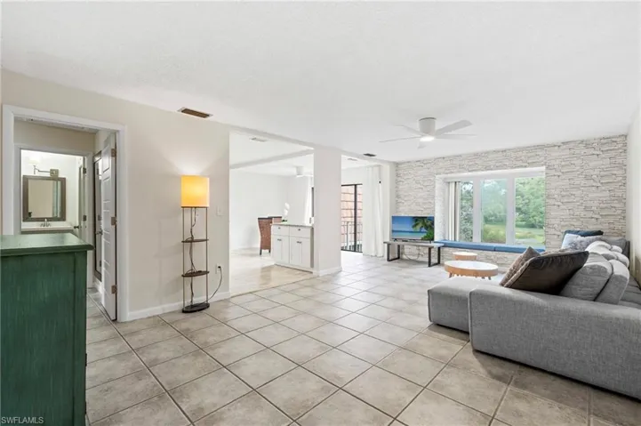 Living room featuring a ceiling fan, light tile patterned flooring, and baseboards