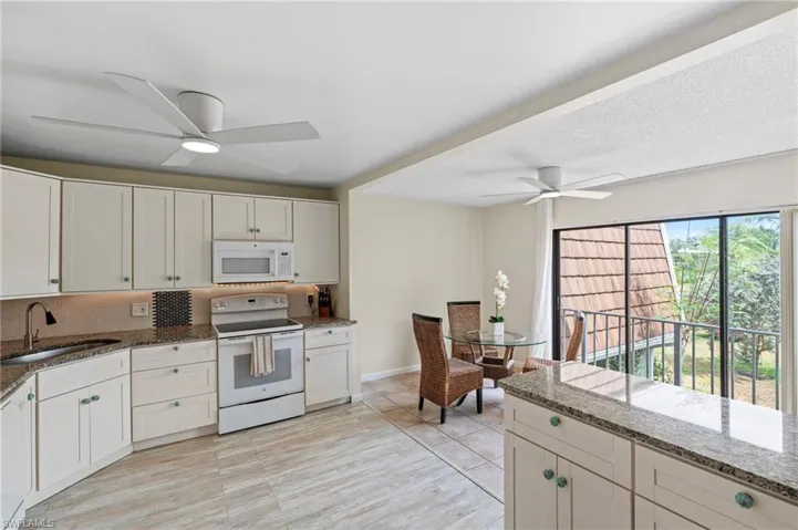 Kitchen featuring white appliances, a sink, a ceiling fan, stone countertops, and backsplash