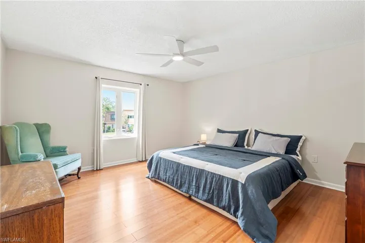 Bedroom featuring light wood-style floors, baseboards, ceiling fan, and a textured ceiling