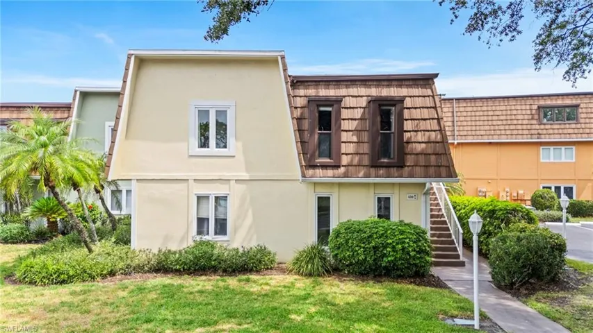 Townhome / multi-family property featuring stucco siding, stairway, mansard roof, and a front yard