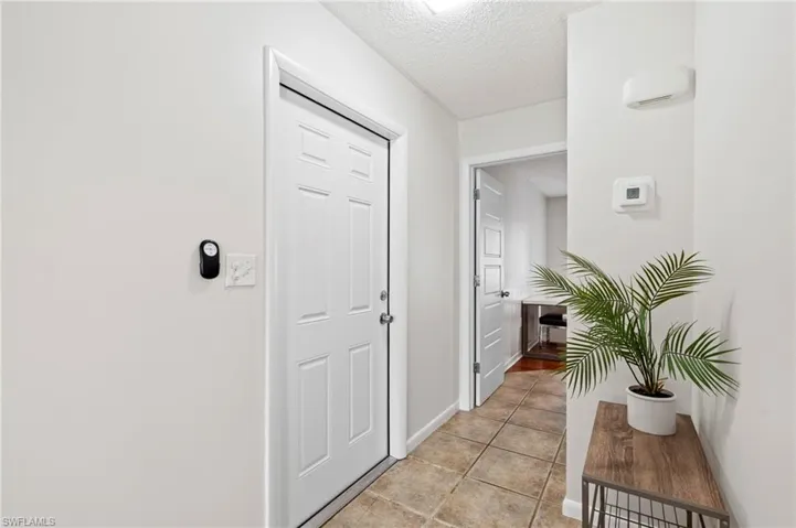 Entryway with a textured ceiling, light tile patterned floors, and baseboards