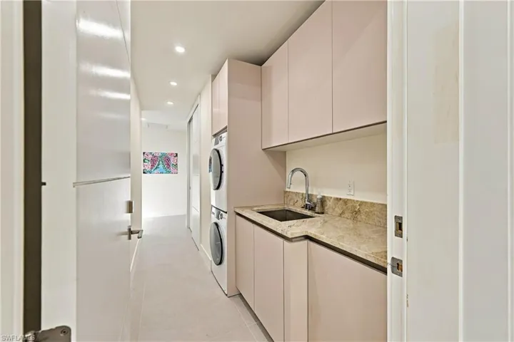 Laundry area featuring flat-panel cabinetry, stone-surface countertop, integrated basin with chrome pull-down faucet, and recessed ceiling lighting