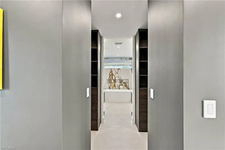 Built-in dark wood cabinetry with integrated shelving, recessed ceiling lighting, and large-format tile flooring