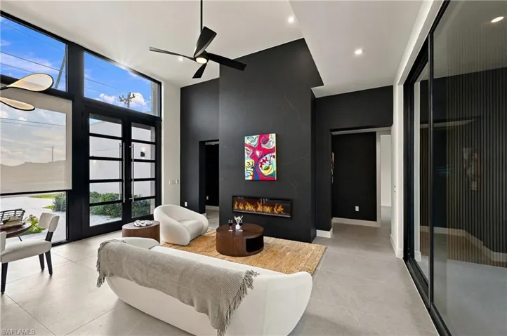 Vaulted ceilings with a ceiling fan, floor-to-ceiling windows, large-format tile flooring, a floor-to-ceiling accent wall, and a built-in linear fireplace