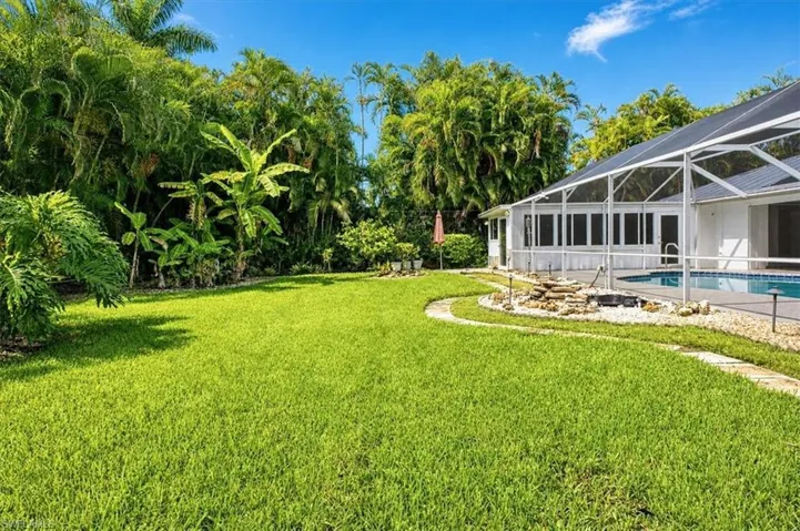 Lots of backyard grassy area beyond the pool deck/cage