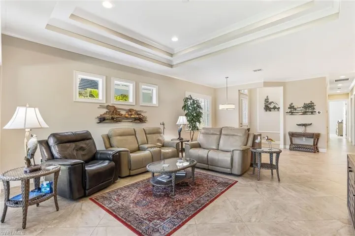 Living room featuring ornamental molding, recessed lighting, and a raised ceiling