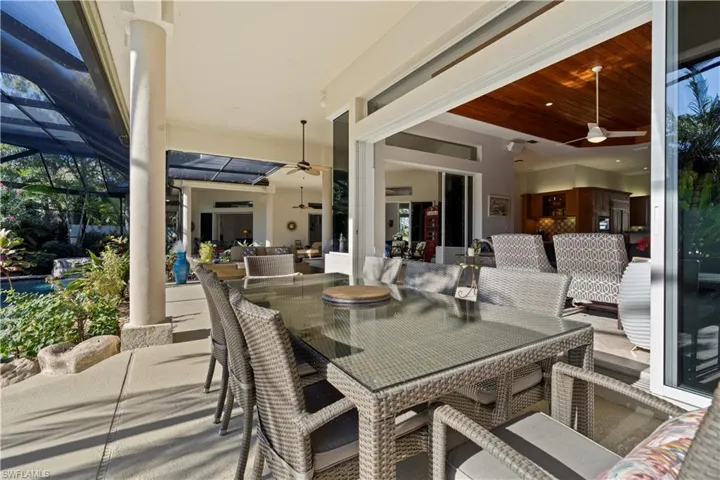 View of patio featuring ceiling fan, glass enclosure, outdoor dining area, and a sunroom