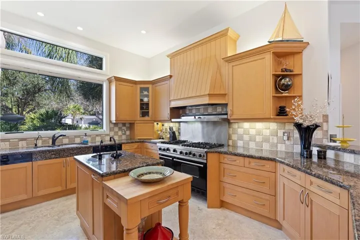 Kitchen with double oven range, custom range hood, dark stone countertops, open shelves, and decorative backsplash