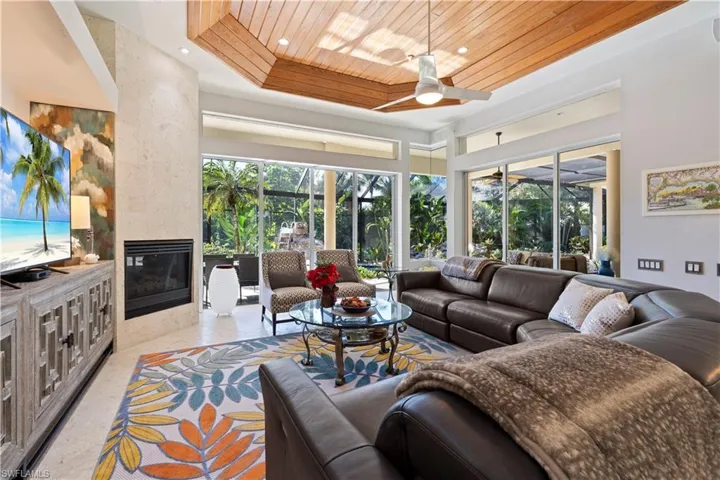 Living area with a tiled fireplace, wood ceiling, a tray ceiling, ceiling fan, and recessed lighting