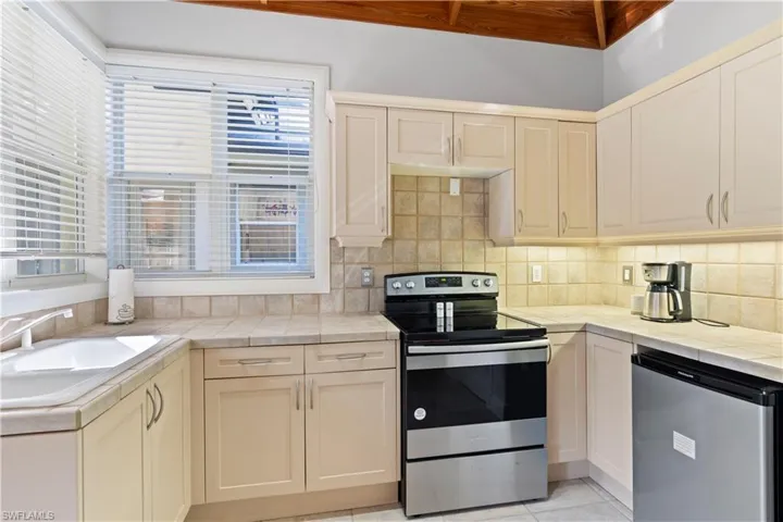 Kitchen featuring stainless steel appliances, tile counters, and decorative backsplash
