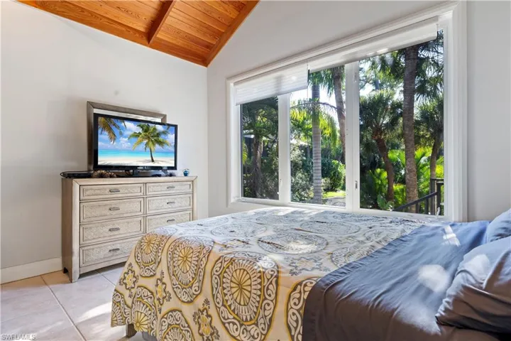 Bedroom featuring light tile patterned floors, vaulted ceiling, wooden ceiling, and access to outside