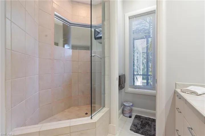 Bathroom featuring plenty of natural light, a shower stall, light tile patterned floors, and vanity