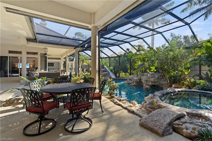 View of patio featuring an in-ground hot tub, glass enclosure, an outdoor pool, a sunroom, and outdoor dining area