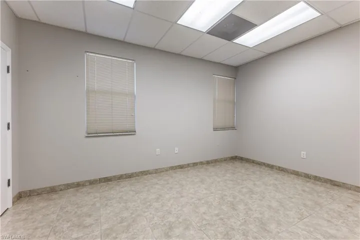 Empty room with a paneled ceiling and light tile patterned floors
