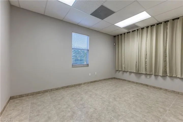 Empty room featuring a paneled ceiling and light tile patterned floors
