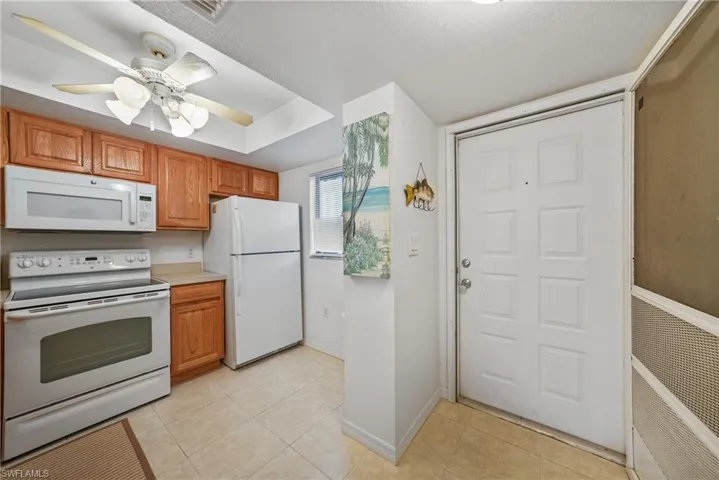 Kitchen featuring white appliances, light countertops, light tile patterned floors, a ceiling fan, and a textured ceiling