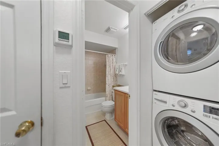 Washroom with estacked washer and dryer and light tile patterned flooring