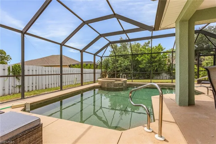 View of swimming pool featuring glass enclosure, an in ground hot tub, and a patio