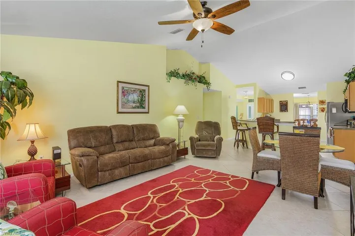 Living room with tile flooring, ceiling fan, and vaulted ceiling