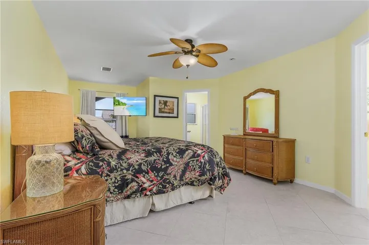 Tiled bedroom featuring ensuite bathroom and ceiling fan