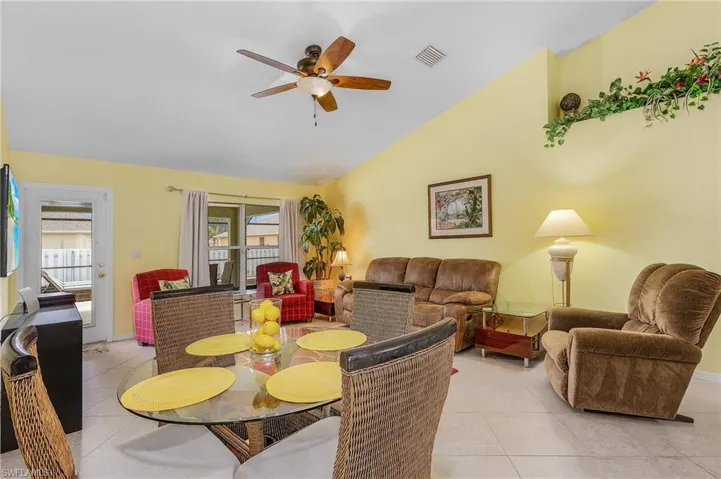 Dining space featuring light tile floors, ceiling fan, and vaulted ceiling
