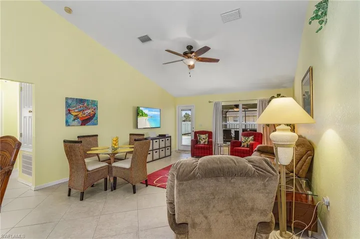 Living room with high vaulted ceiling, ceiling fan, and light tile flooring