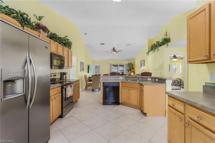 Kitchen featuring ceiling fan, vaulted ceiling, kitchen peninsula, and black appliances