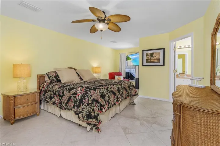 Bedroom with tile flooring, ceiling fan, and ensuite bath