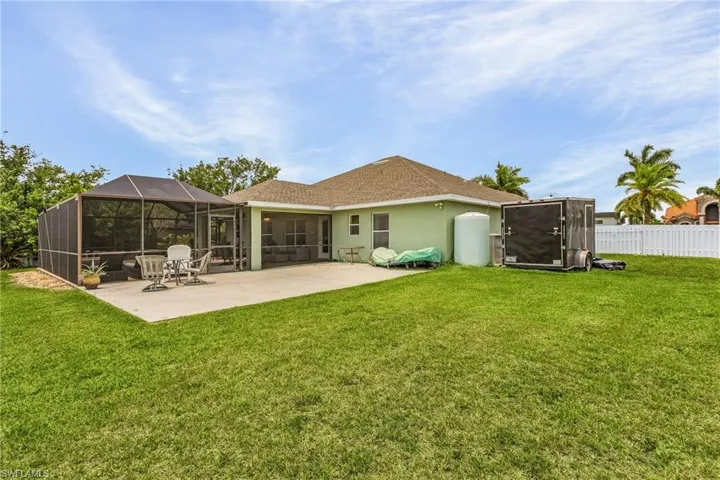 Rear view of house featuring a patio, a lanai, and a lawn