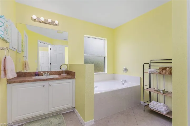 Bathroom with tile flooring, a relaxing tiled bath, and vanity with extensive cabinet space