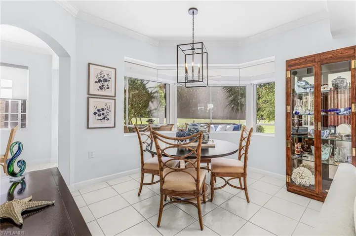 Bay window with expansive glass, ceramic tile flooring, geometric metal pendant light fixture, crown molding, and neutral wall tones