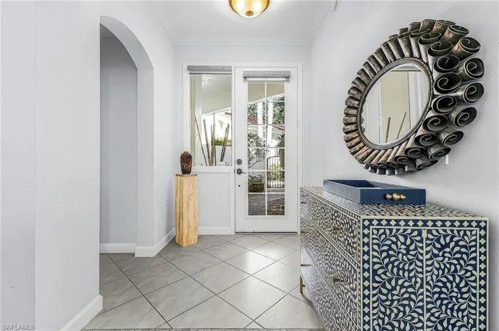 Entryway featuring large-format diagonal tile flooring, an arched threshold, and a glass-paneled entry door with sidelight