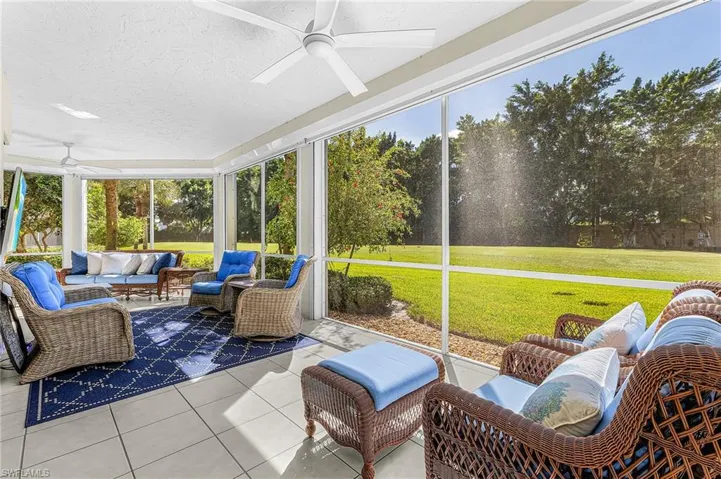 Screened-in lanai featuring large-format tile flooring, dual ceiling fans, and full-height screen panels