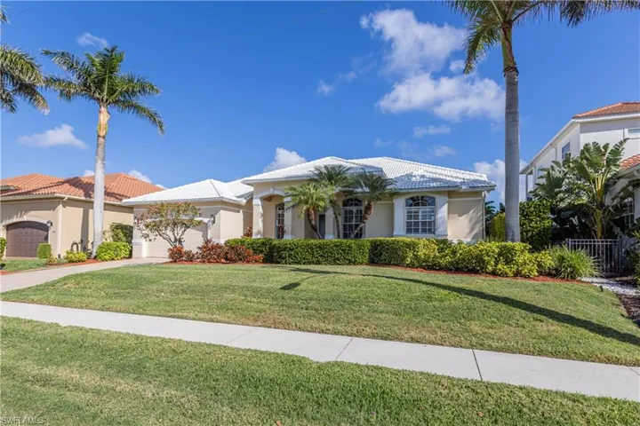 Mediterranean / spanish house featuring a garage, a tiled roof, a front lawn, and stucco siding